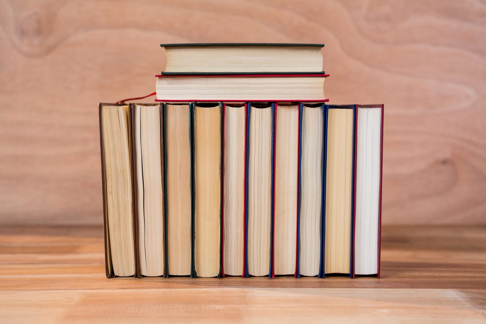 Fileira de livros de capa dura enfileirados sobre uma mesa de madeira.